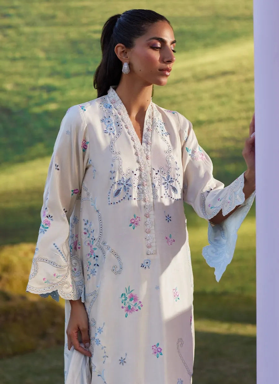 Woman wearing a white embroidered dress standing in a grassy field