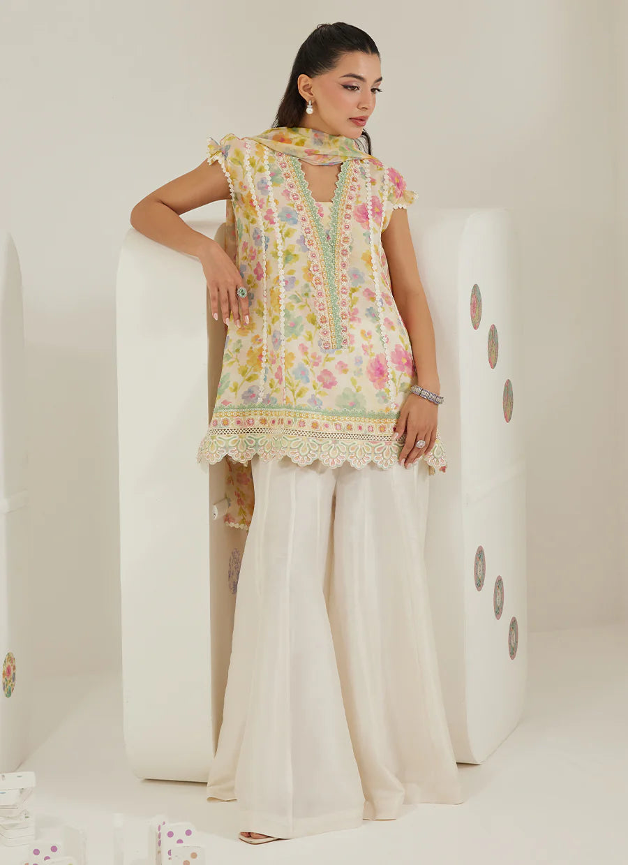 Woman wearing a floral top and white pants against a plain background