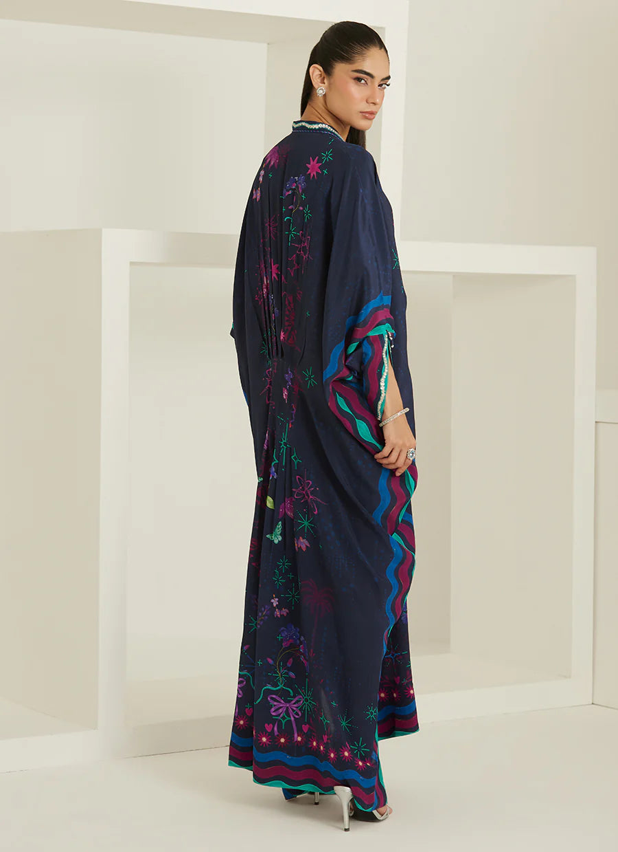 Woman wearing a dark blue saree with colorful patterns in a minimalistic setting