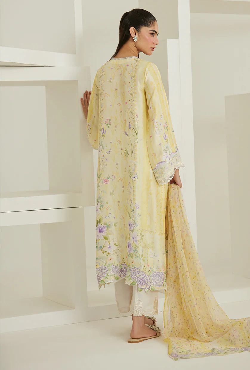 Woman in a light yellow floral dress standing in a minimalistic room.