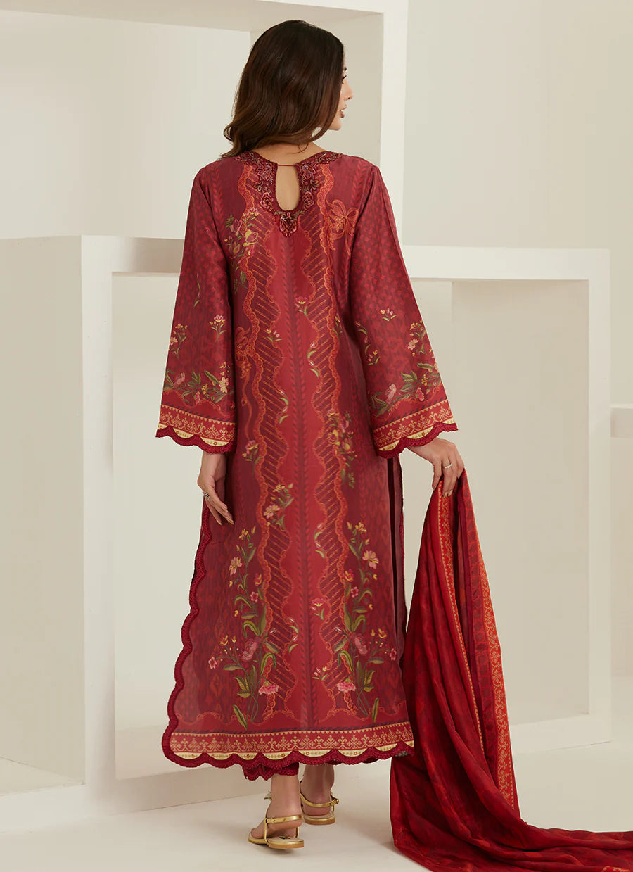 Woman wearing a red embroidered traditional outfit with a matching dupatta in a minimalistic setting.
