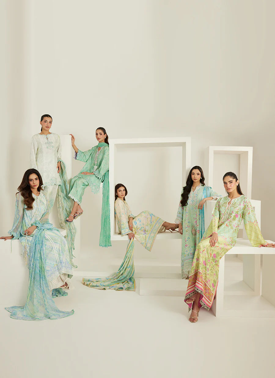 Five women in colorful traditional outfits posing in a minimalistic setting.