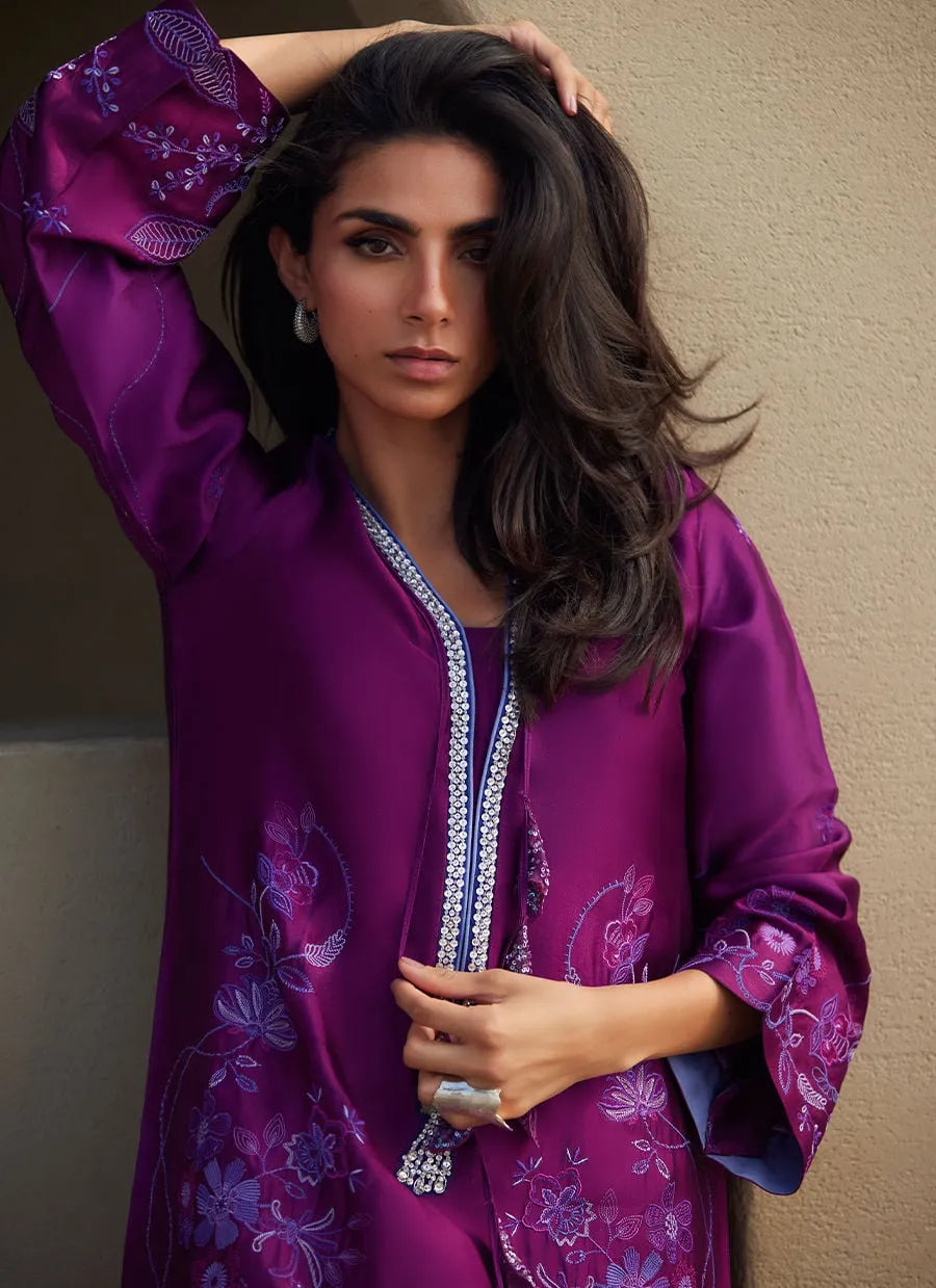 Woman wearing a purple embroidered outfit against a beige background