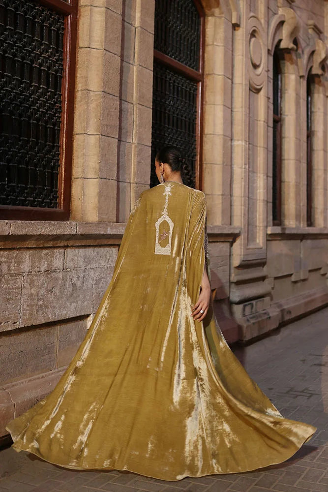 Person wearing a long, flowing gold dress with a building in the background