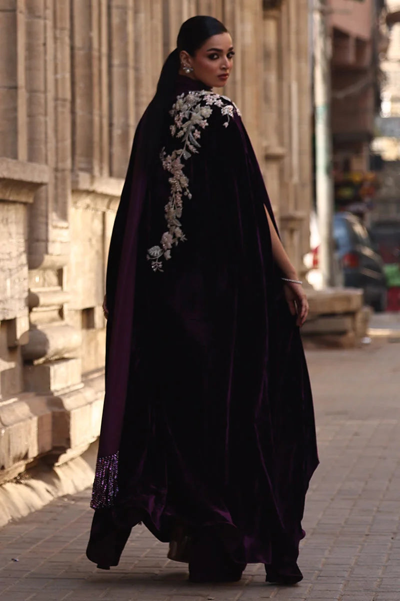 Woman in a black abaya with floral embroidery walking on a street.