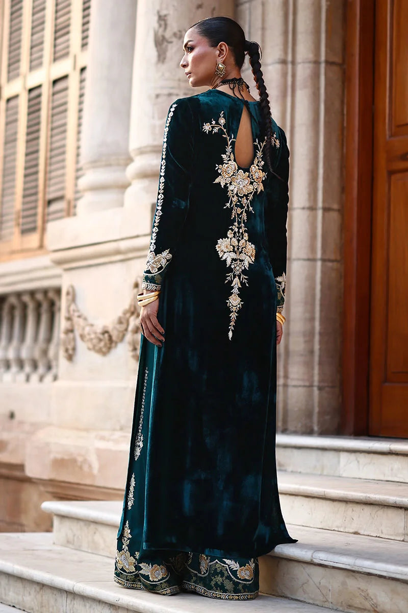 Woman in a dark green embroidered outfit standing on steps with classical architecture in the background