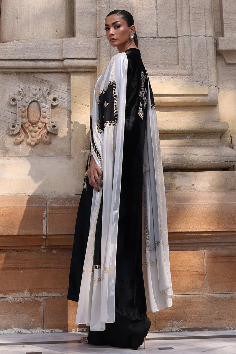 Woman in a black and white traditional outfit standing on stone steps.