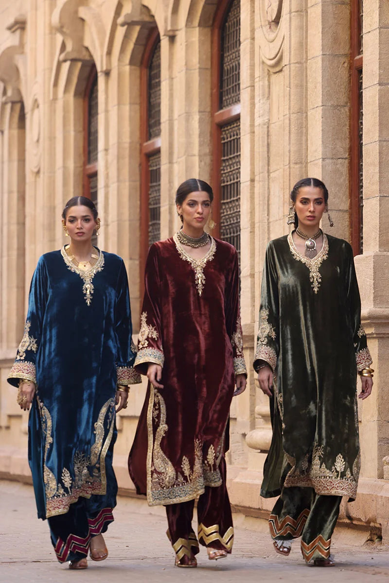 Three women in traditional outfits walking together in front of a stone building.