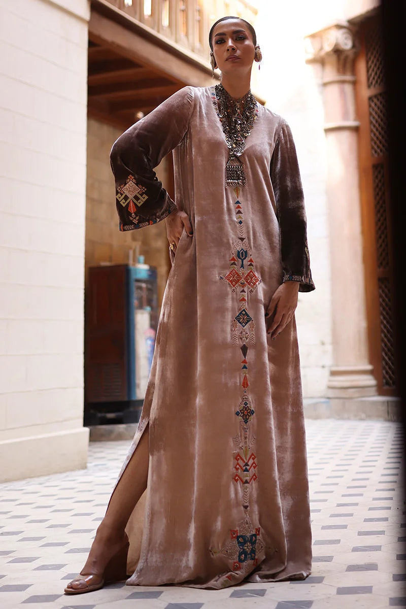 Woman wearing a long, embroidered dress in an outdoor setting.