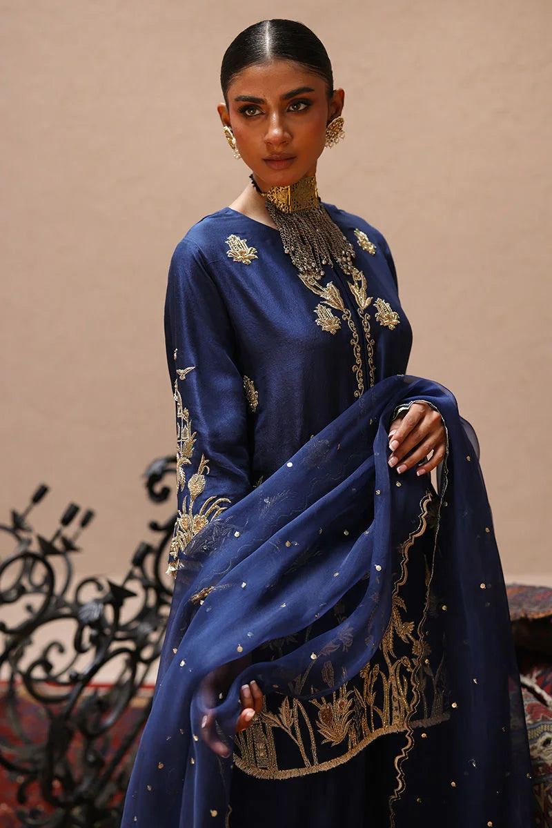 Woman wearing a blue embroidered traditional outfit with a beige background