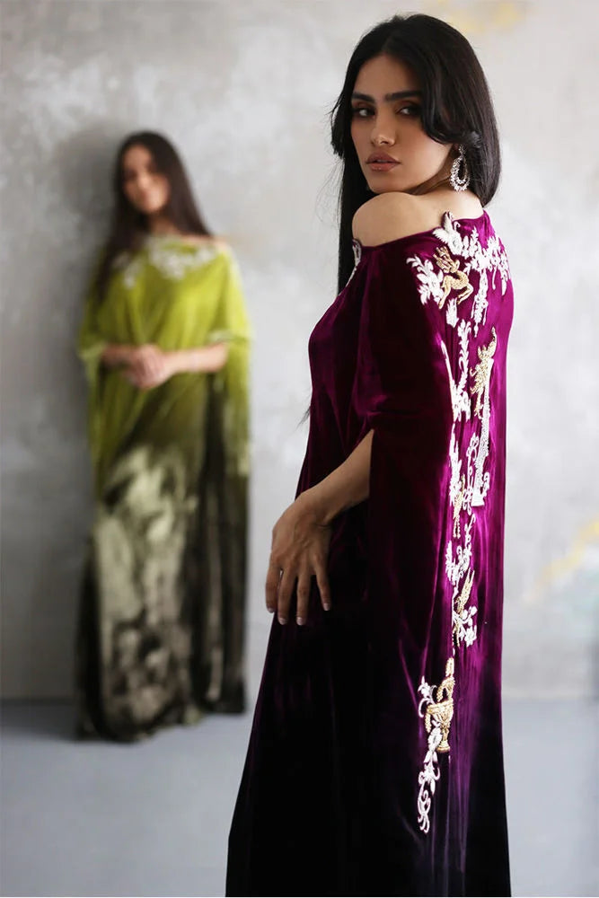 Woman wearing a purple dress with floral embroidery in front of a blurred background
