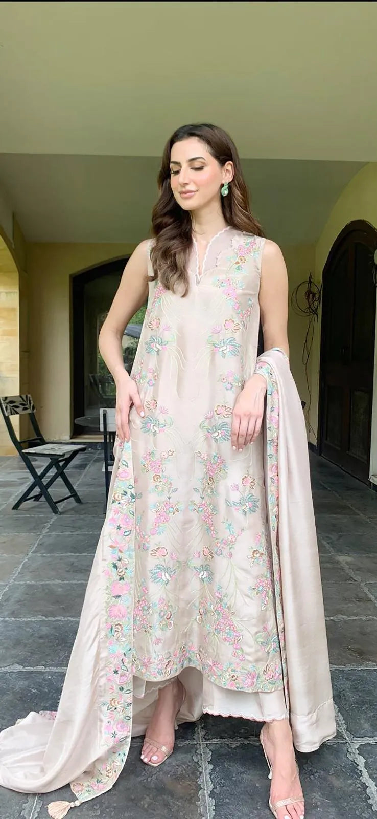 Woman in a floral dress standing outdoors on a stone path.
