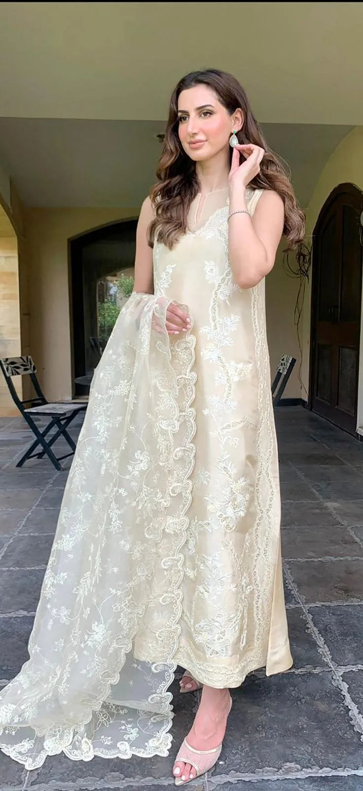 Woman in a white floral dress standing outdoors.