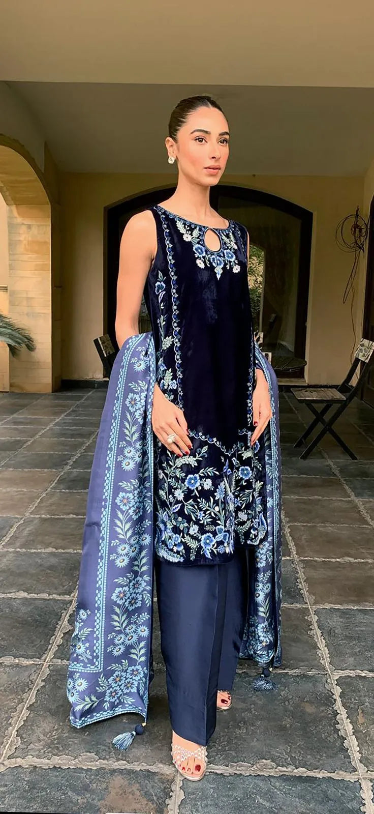 Woman in a navy blue outfit with floral patterns standing on a stone path.