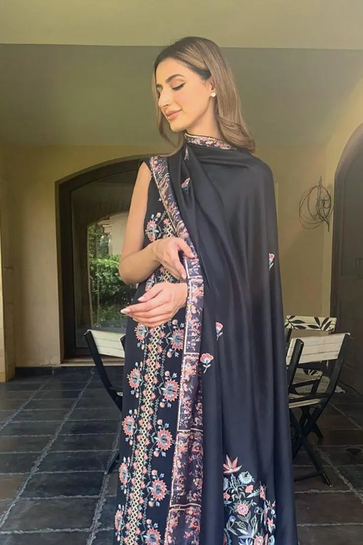 Woman wearing a dark blue embroidered saree with a floral pattern indoors.