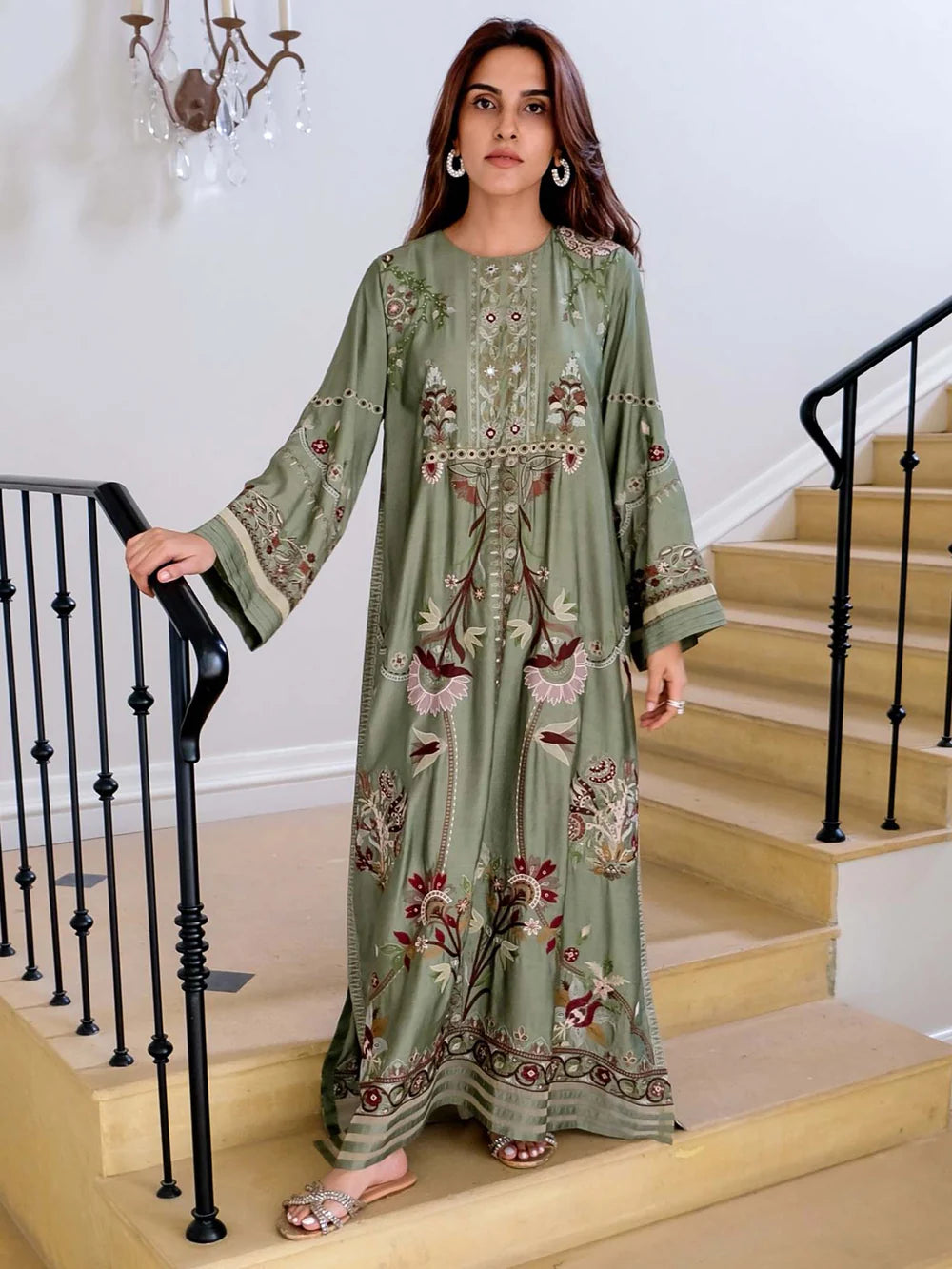Woman in a green embroidered dress standing on a staircase