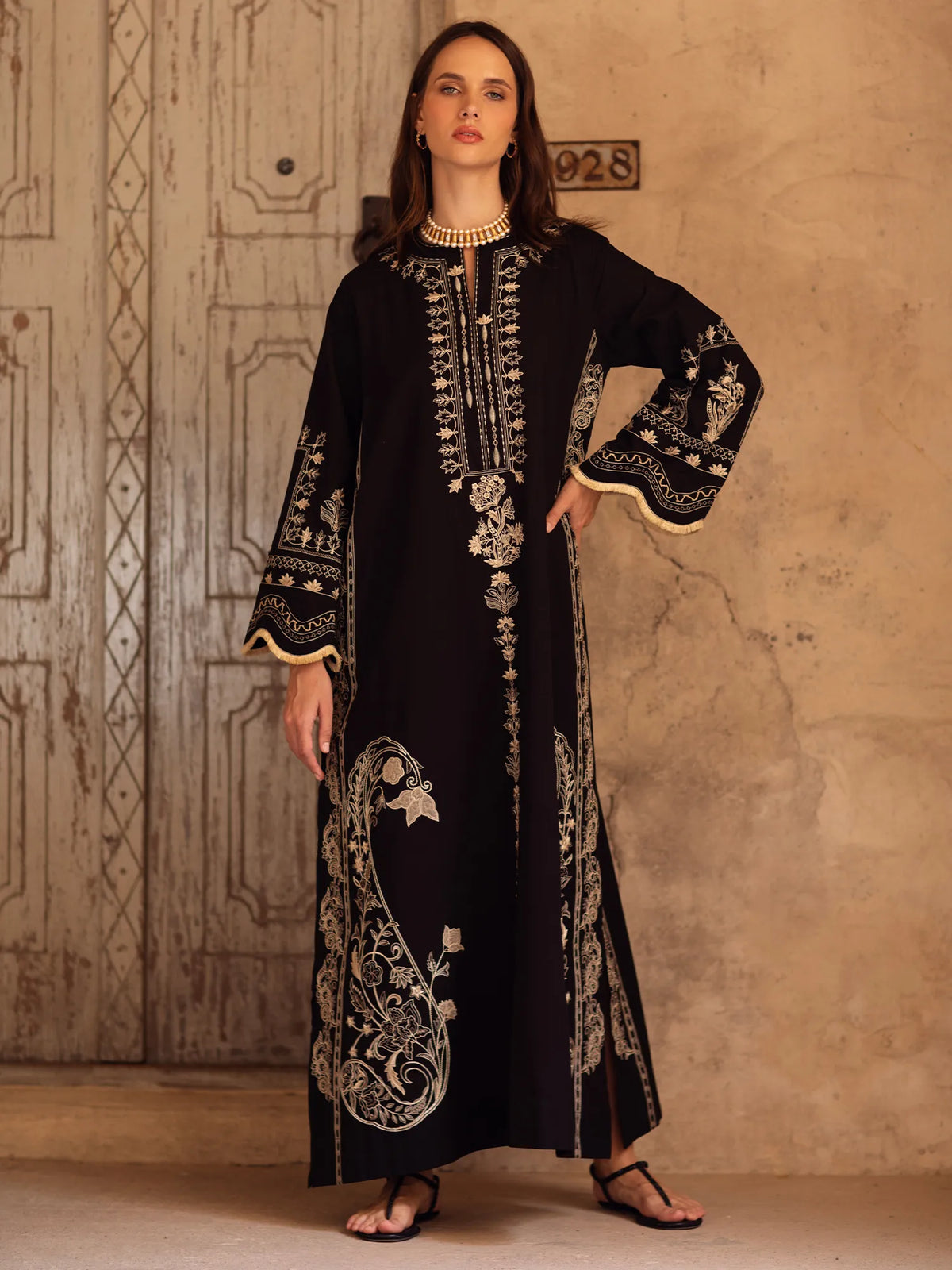 Woman wearing a black embroidered dress in a rustic setting