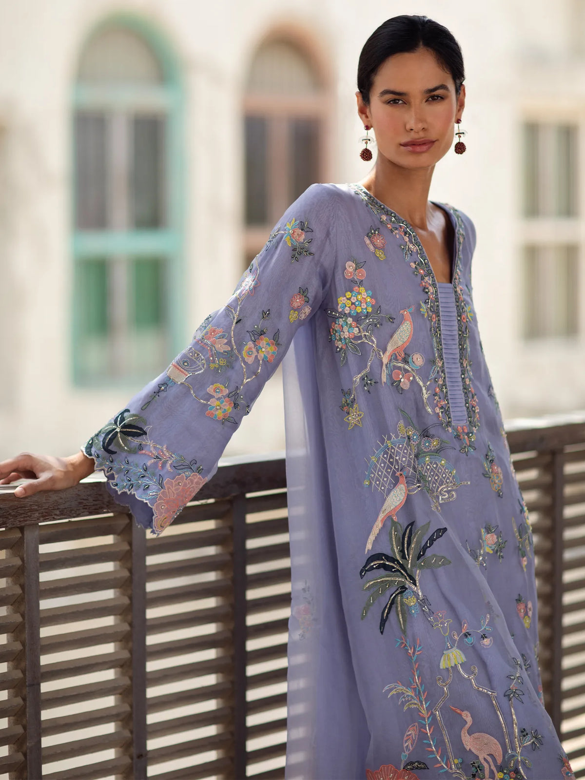 Woman wearing a light purple embroidered dress standing outdoors.