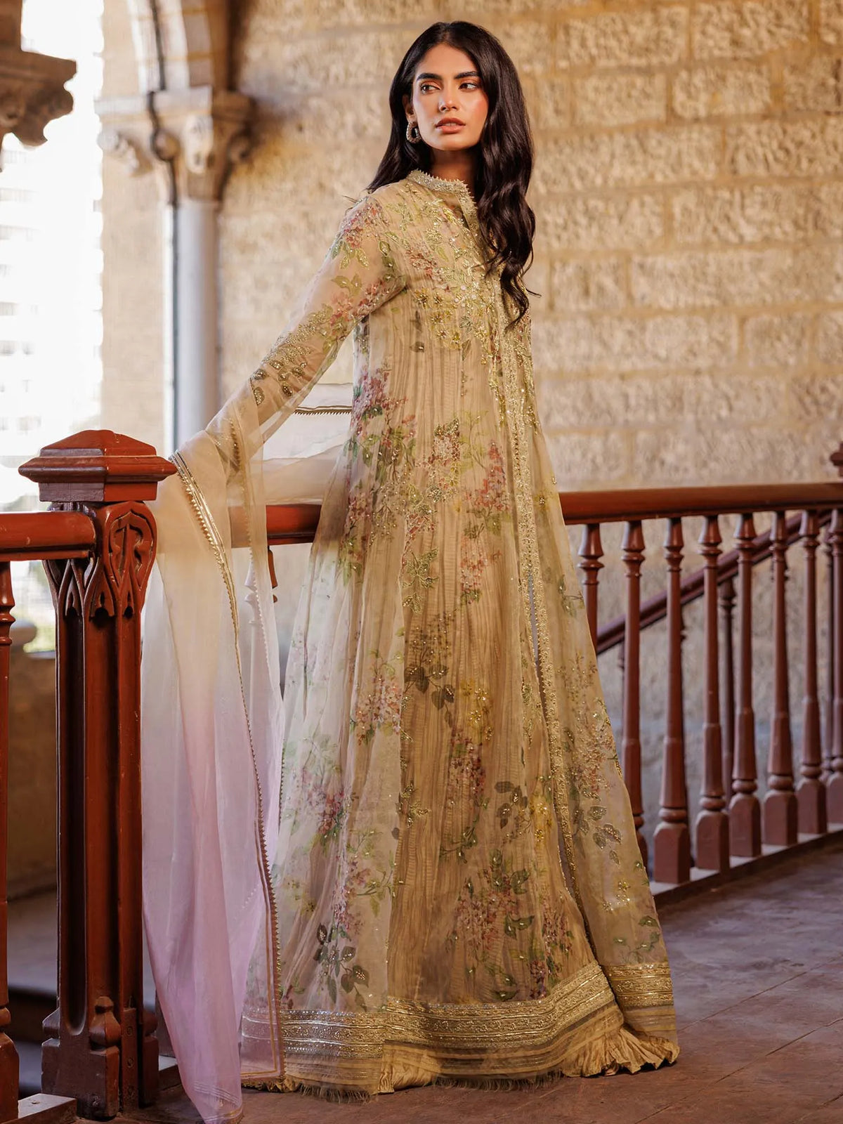 Woman in a traditional embroidered outfit standing in an elegant interior setting.