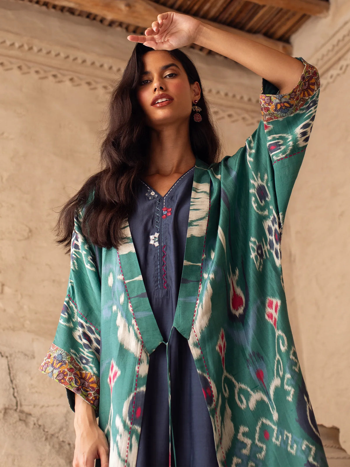 Woman wearing a green patterned kimono-style garment indoors.