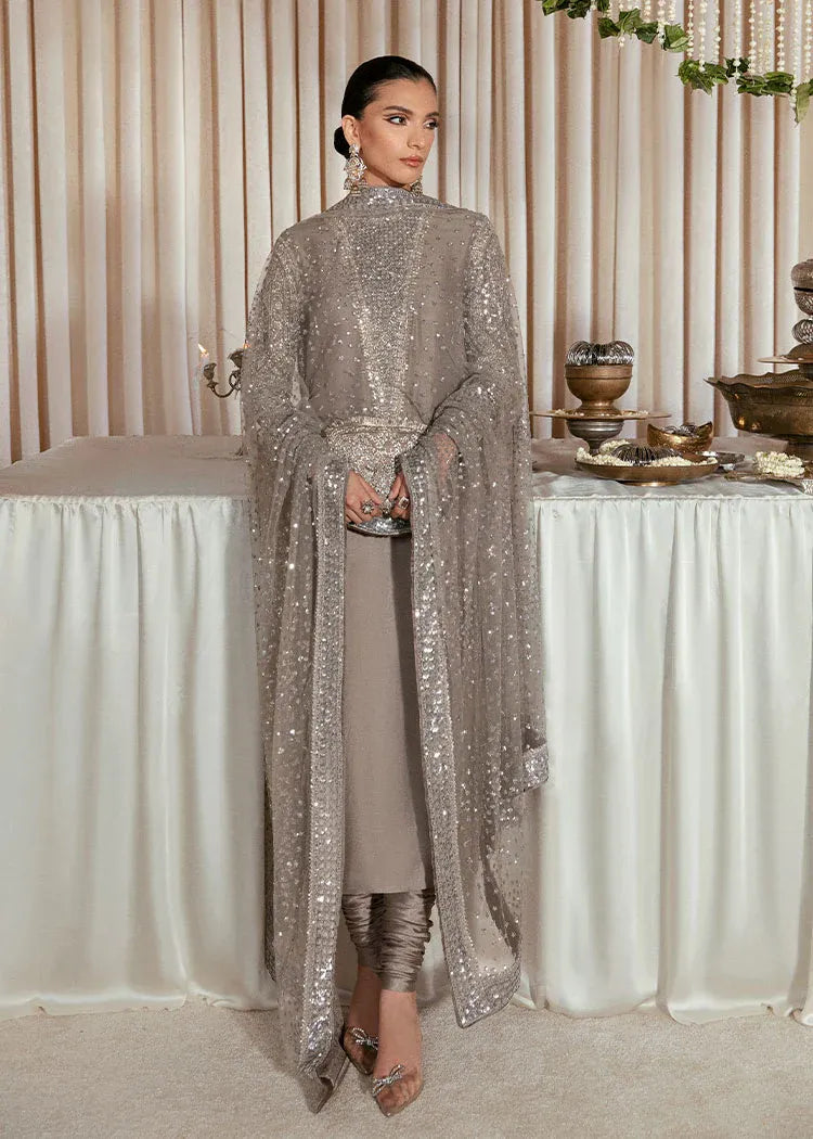 Woman in a sparkly silver outfit standing in front of a decorated table with a neutral curtain background