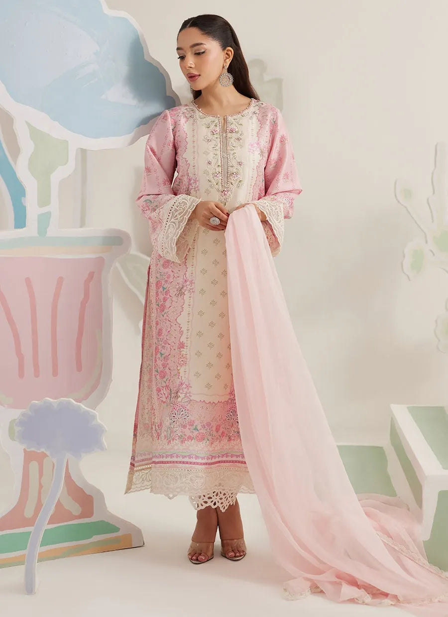 Woman wearing a traditional outfit with pink and white embroidery in a decorative setting.