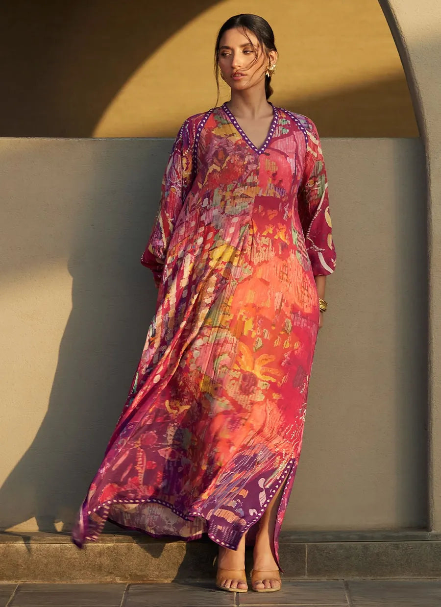 Woman wearing a colorful patterned dress standing against a wall.