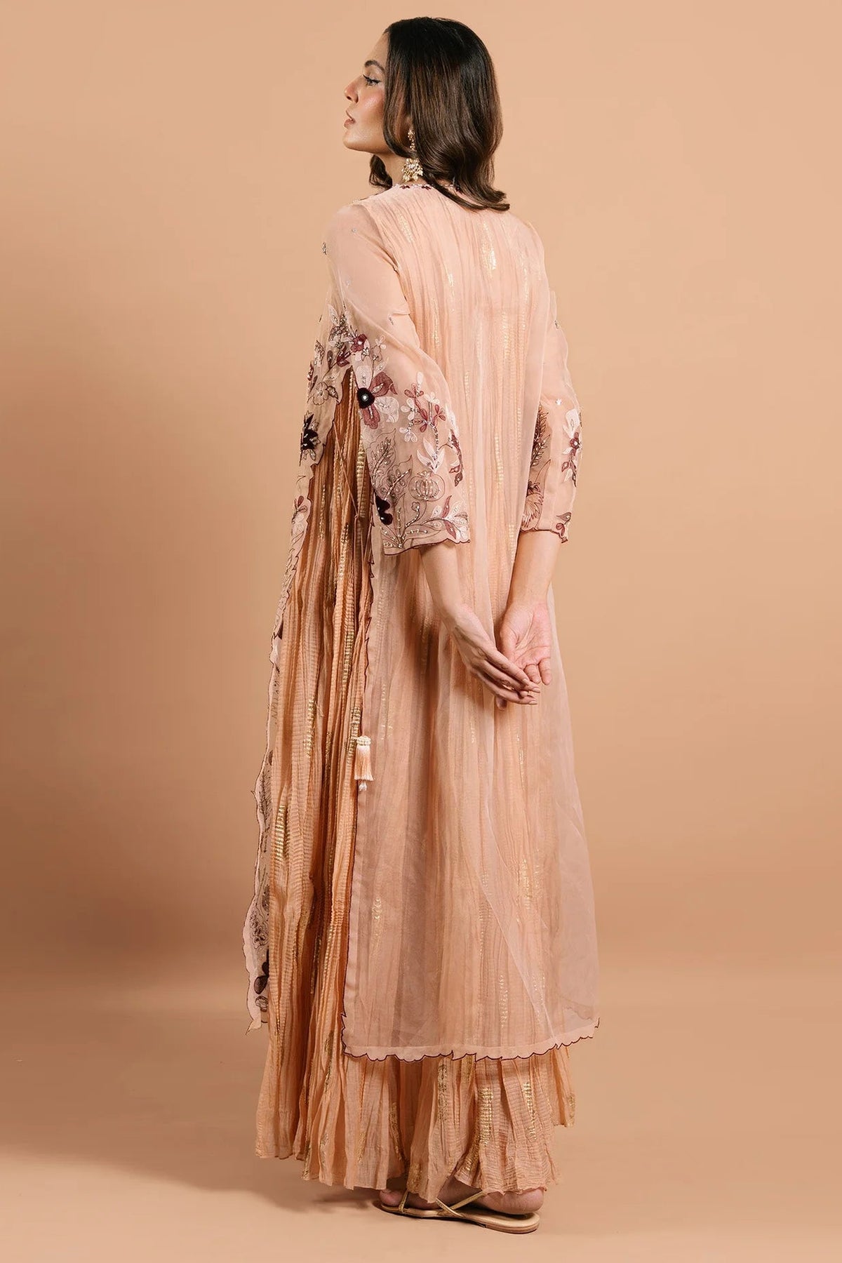 Woman wearing a peach-colored outfit with floral patterns on a beige background