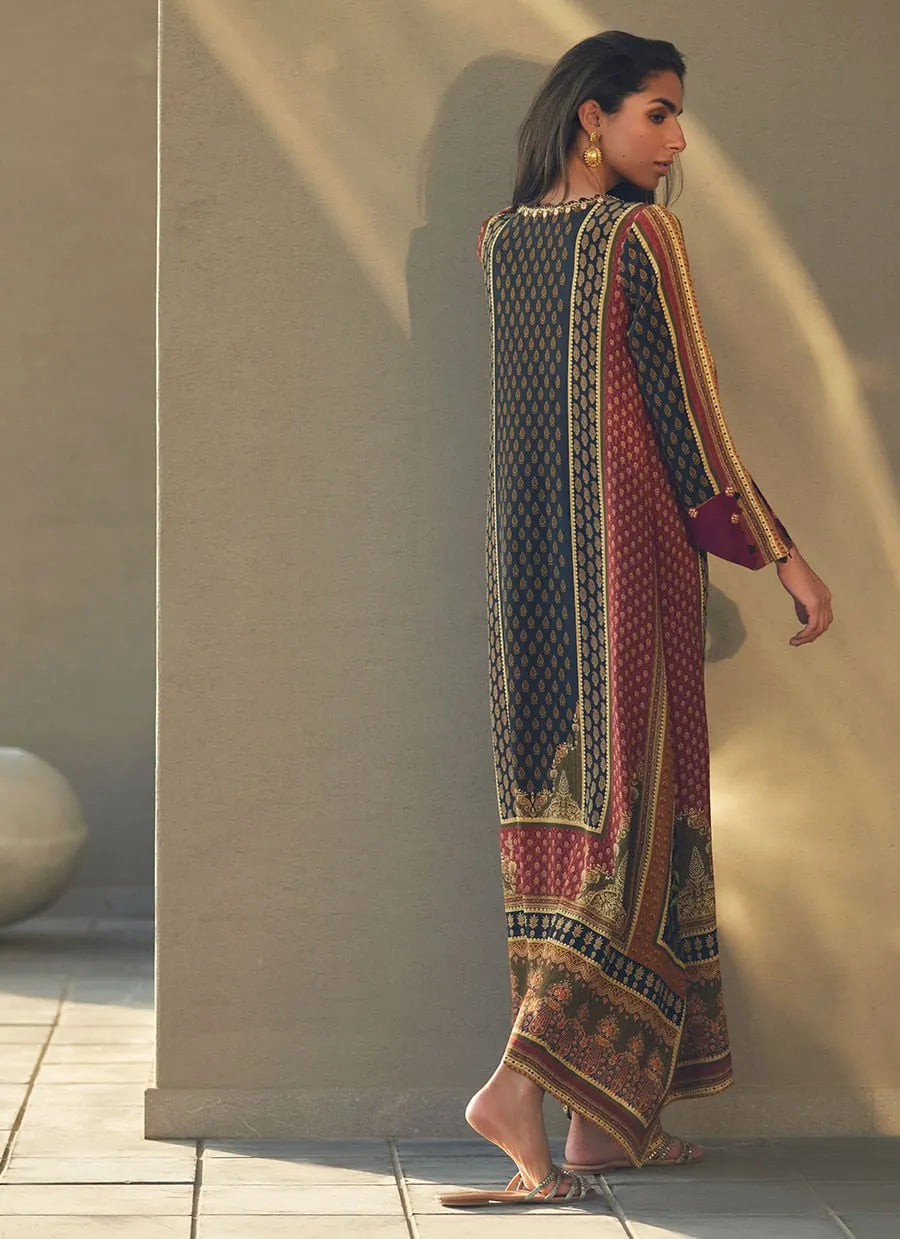 Woman wearing a patterned dress standing against a neutral wall.
