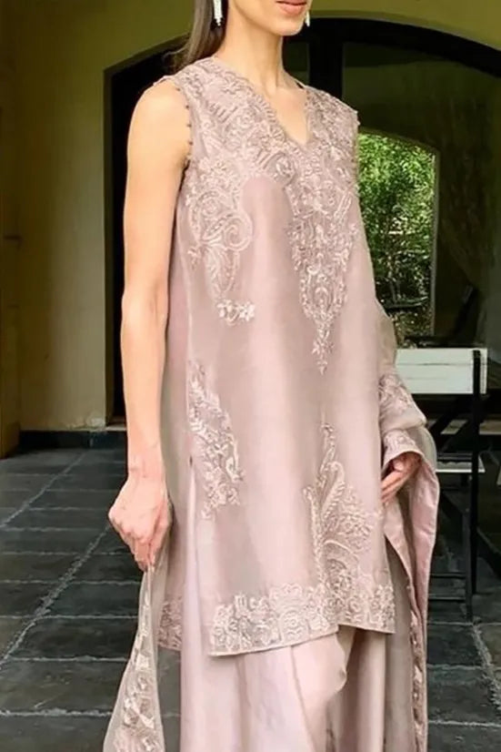 Woman wearing a light pink embroidered dress with a matching dupatta in an outdoor setting.