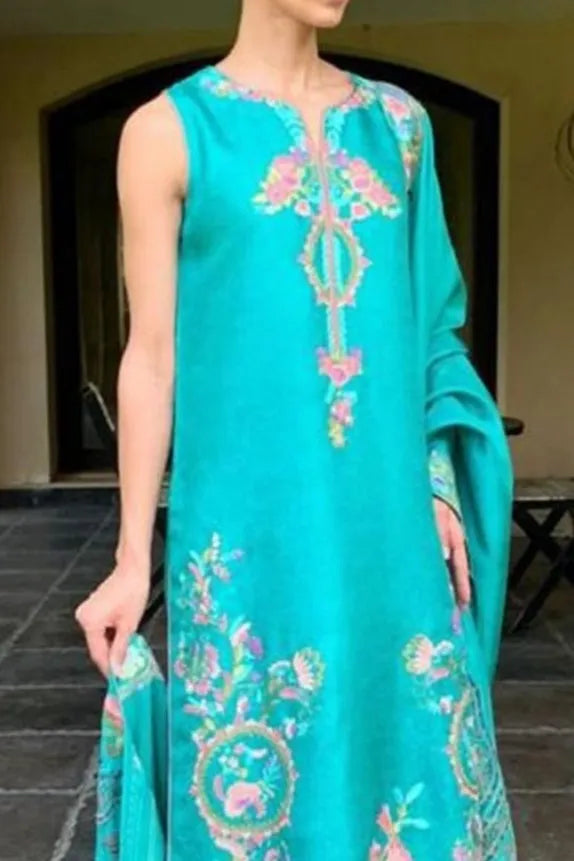 Turquoise embroidered dress worn by a model outdoors.