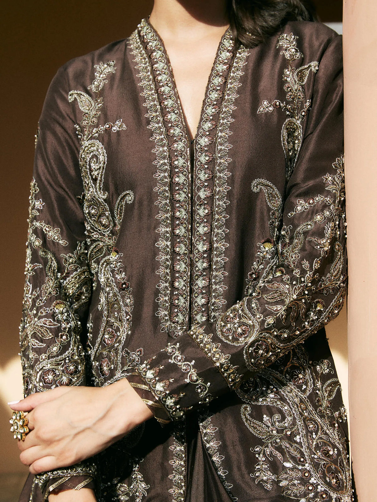 Brown embroidered garment with intricate patterns on a neutral background