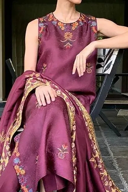 Person wearing a purple embroidered traditional outfit sitting on a chair.