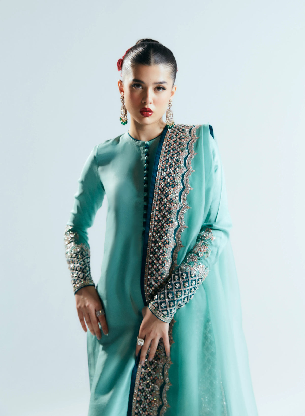 Woman wearing a light blue traditional outfit with intricate patterns on a white background