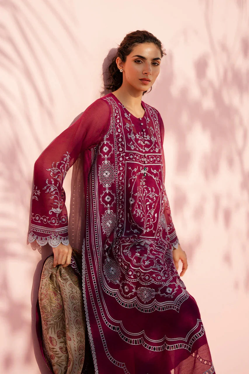 Woman wearing a maroon embroidered traditional outfit against a pink background