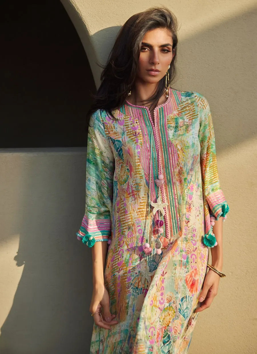 Woman wearing a colorful patterned dress against a beige wall.