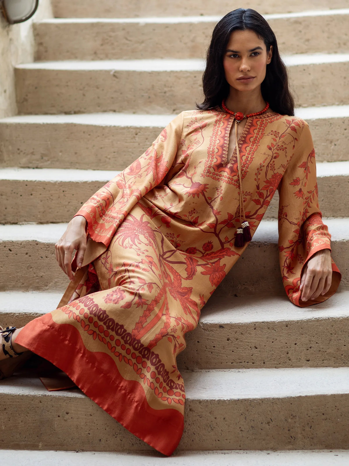 Woman in a patterned dress sitting on stone steps