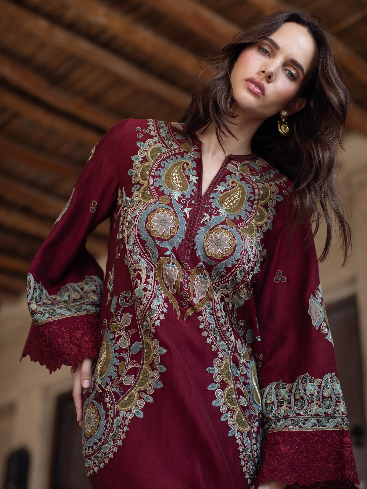 Woman wearing a burgundy dress with intricate patterns in an indoor setting