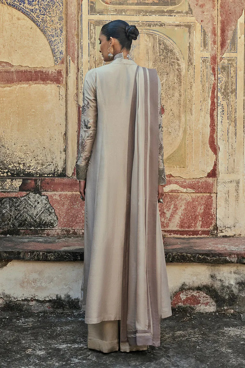 Woman in a long, light-colored dress with a patterned background