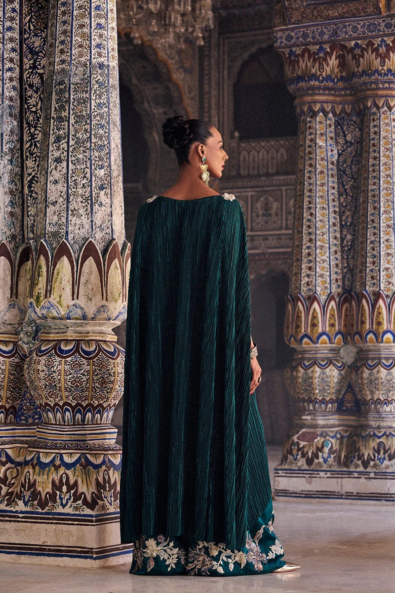 Woman in a green dress standing in front of ornate wall designs