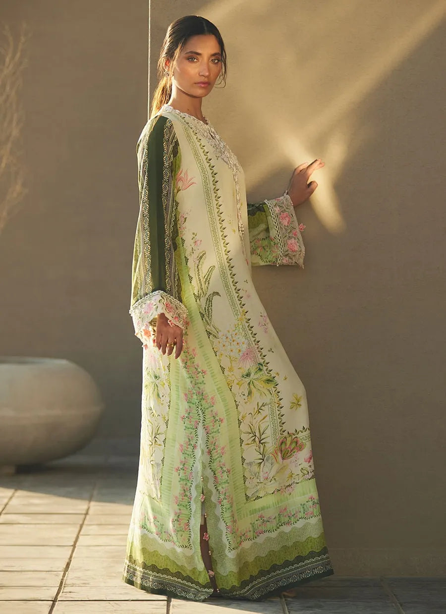 Woman wearing a light green embroidered traditional outfit against a beige wall.
