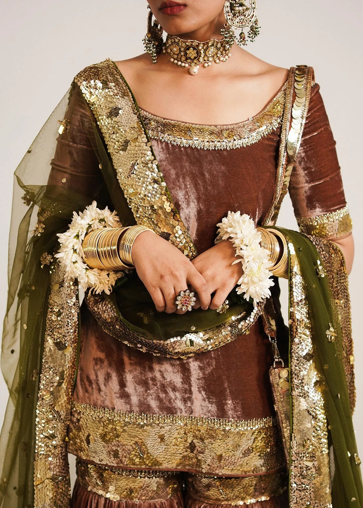 Traditional outfit with gold and brown details, holding a decorative basket.