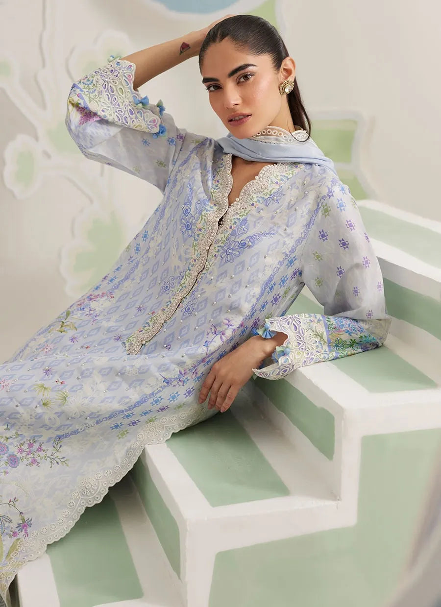 Woman wearing a floral dress sitting on a green chair with a white background