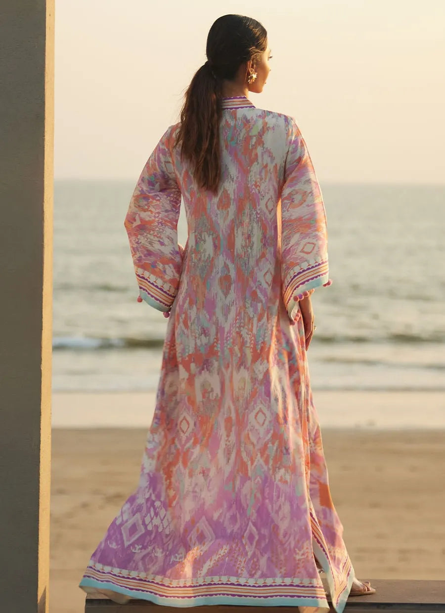 Woman in a colorful dress standing on a beach with sunset in the background