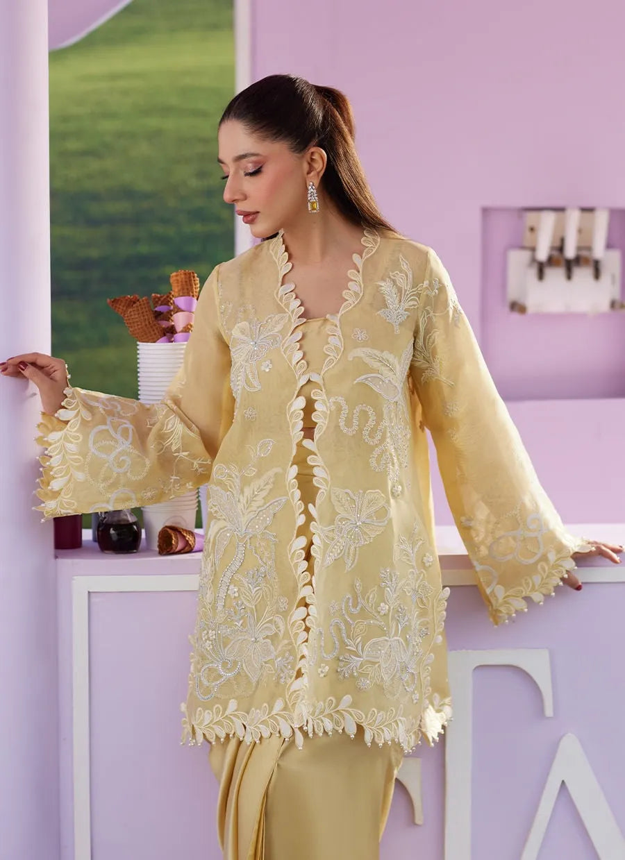 Woman wearing a yellow embroidered outfit in a room with a pink wall.