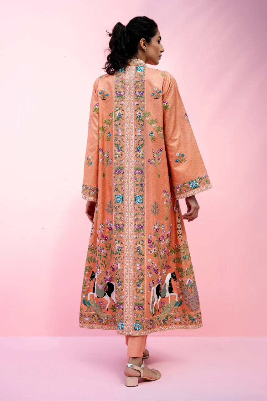 Woman wearing a peach-colored embroidered outfit on a pink background