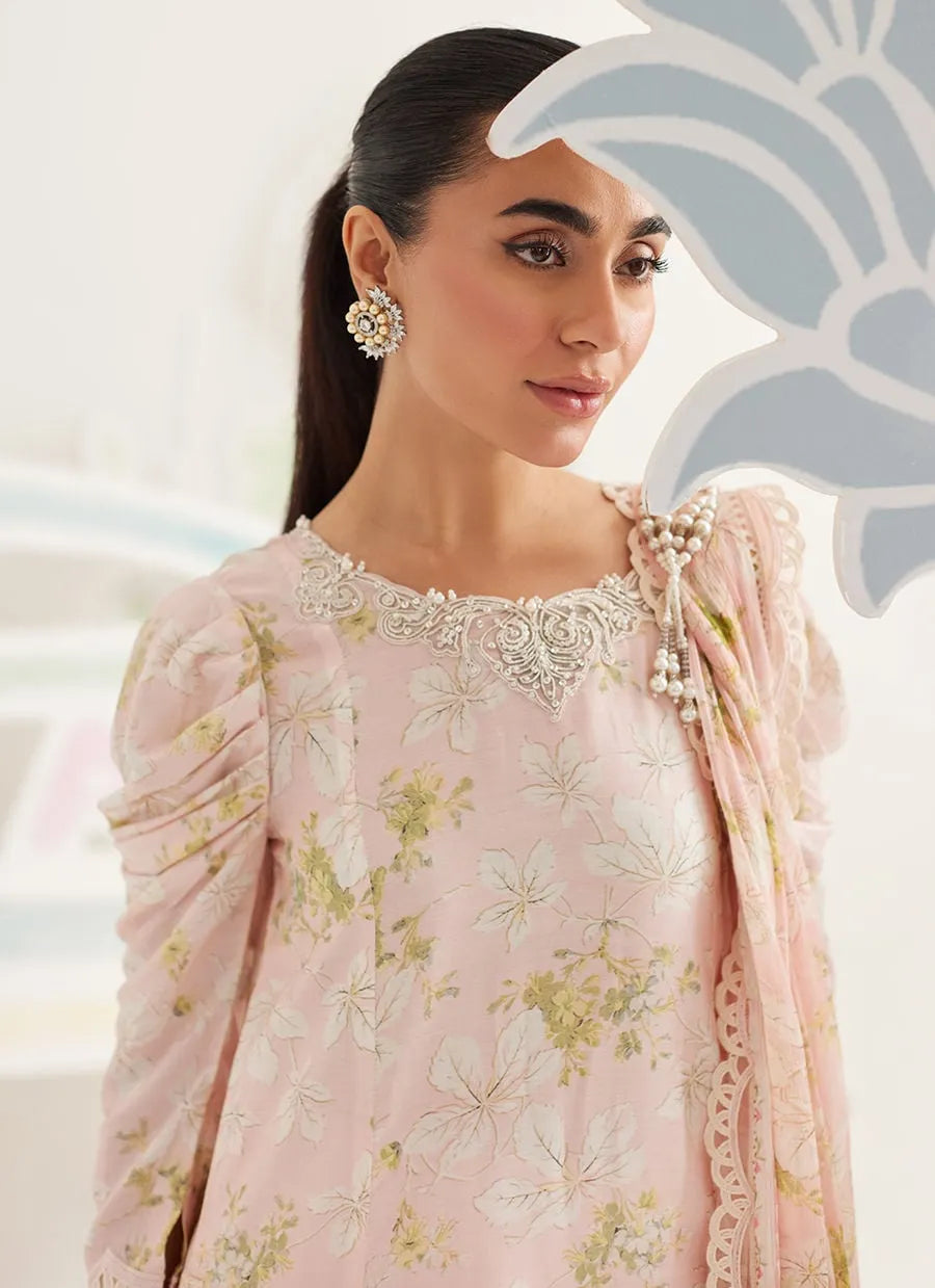 Woman wearing a light pink embroidered traditional outfit with floral patterns.