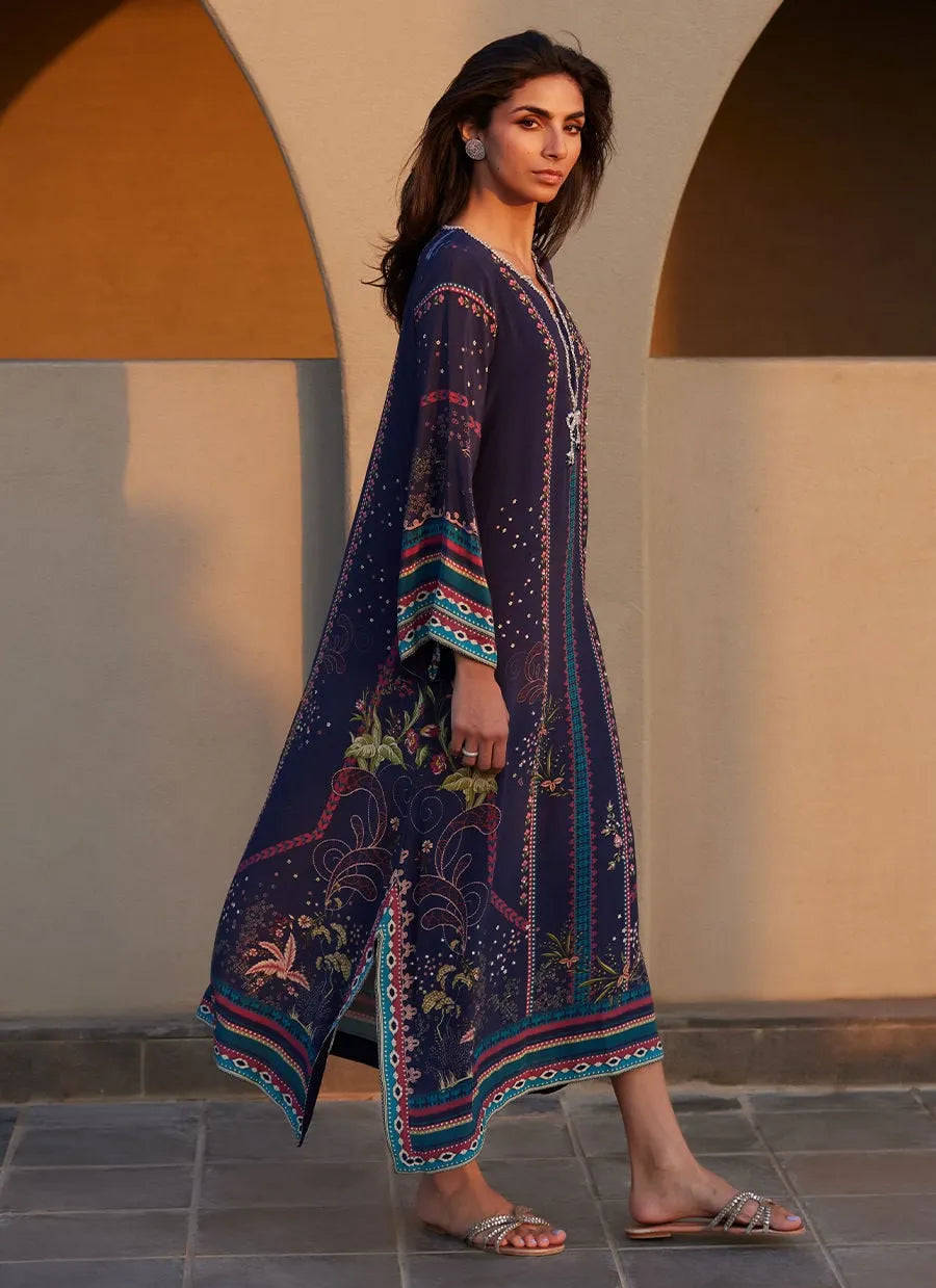Woman wearing a long, patterned dress standing in front of a neutral-colored wall.