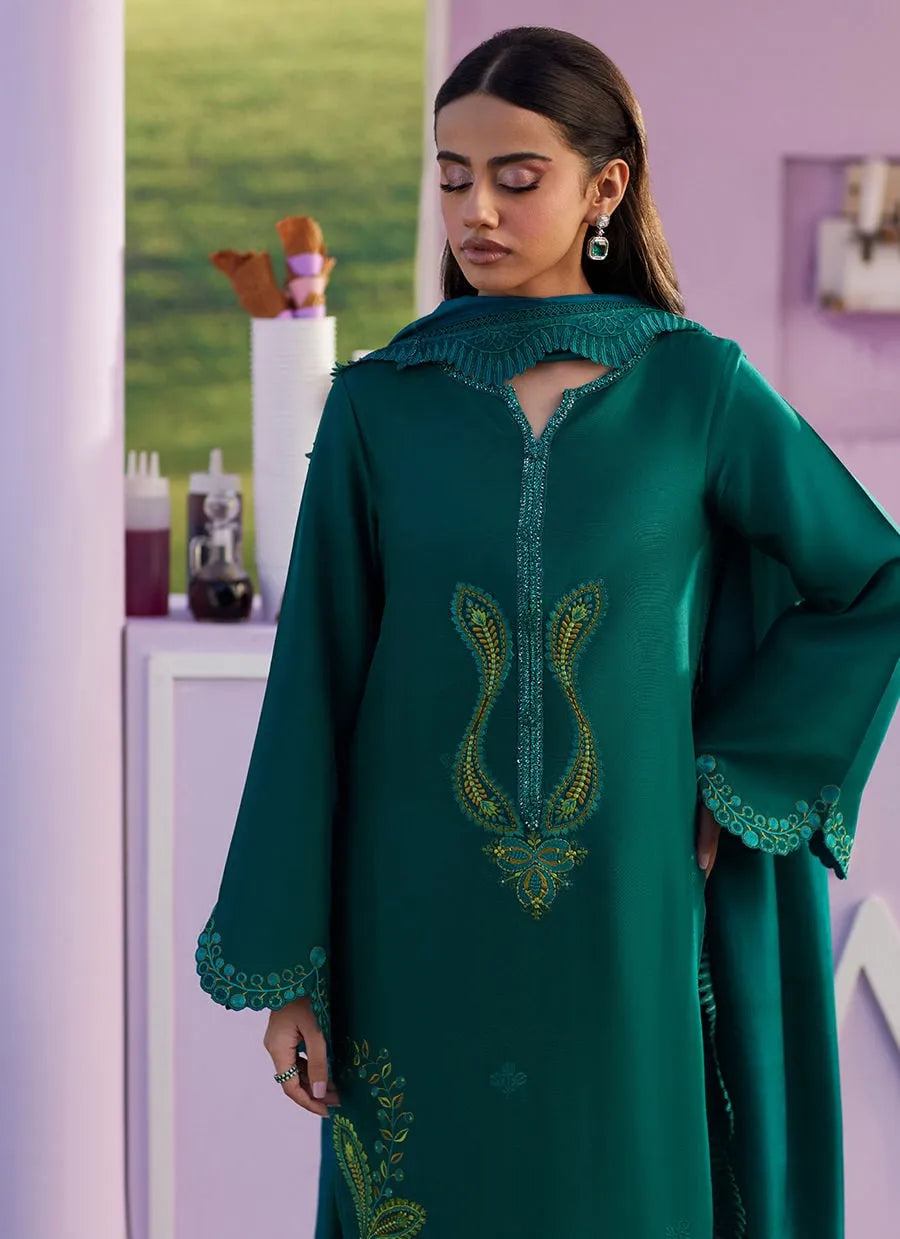 Woman wearing a green embroidered dress in a room with a purple wall.