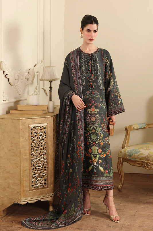 Woman wearing a long, dark-colored dress with floral patterns in a room with wooden furniture and a lamp.